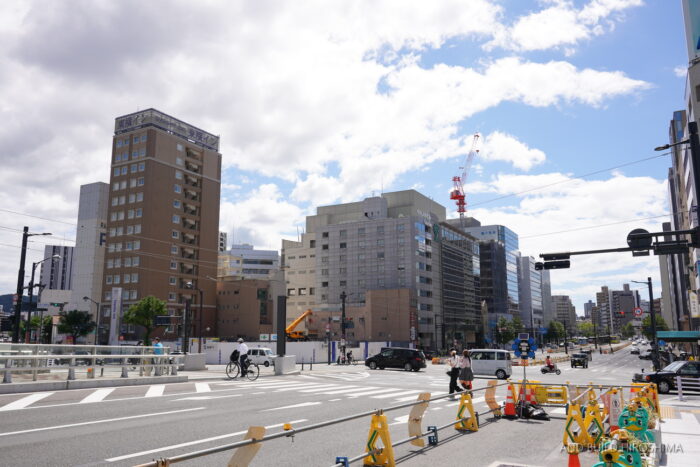 駅前大橋南詰交差点から見たvoco広島の敷地と奥のアパホテル〈広島駅前通〉のタワークレーン